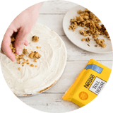 Imagen circular de una mano rociando migas de masa de galletas.