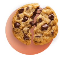 Una galleta con chispas de chocolate partida por la mitad con chocolate derretido contra un círculo degradado naranja.