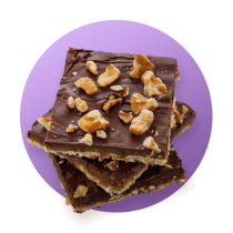 Tres trozos de caramelo salado decorados con nueces y chocolate en un círculo con fondo degradado de color morado.