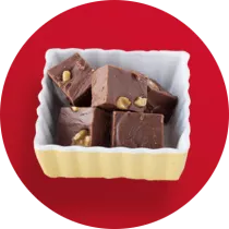 A square white dish filled with 5 fudge squares with nuts in front of a red circle.