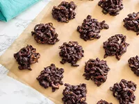 Tres galletas decoradas con glaseado rojo y blanco para que parezcan mariquitas sobre un plato verde.